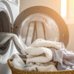 Una lavatrice aperta con il bucato che cade dentro una cesta