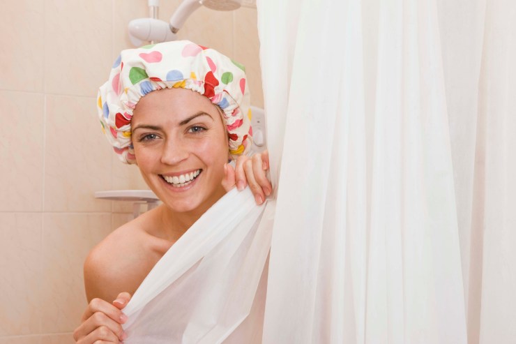 Che fa capolino dalla doccia e sorride con in testa una cuffia