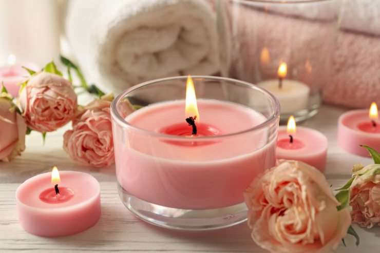 Delle candele profumate rosa messe vicino delle rose rosa 