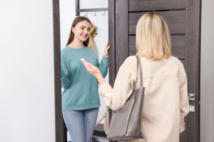 Donna accoglie un'altra donna sull'uscio della porta