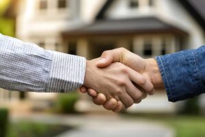 Due persone che si stringono la mano e lo sfondo una casa