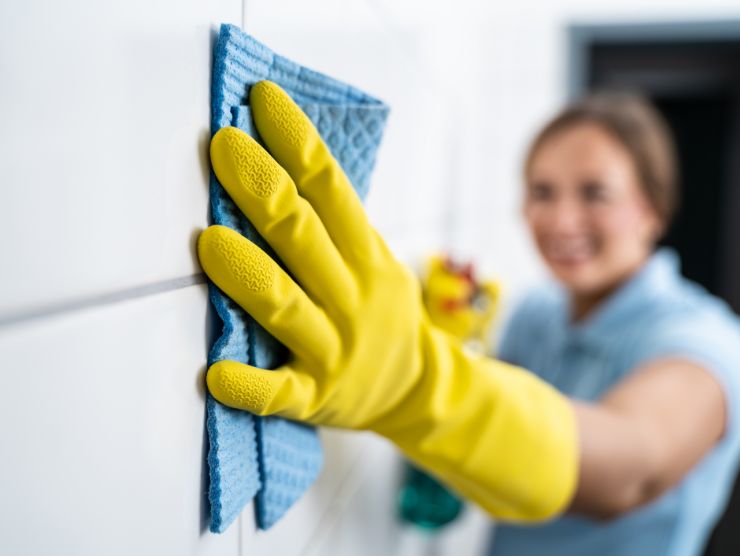 donna pulisce mattonelle bagno 