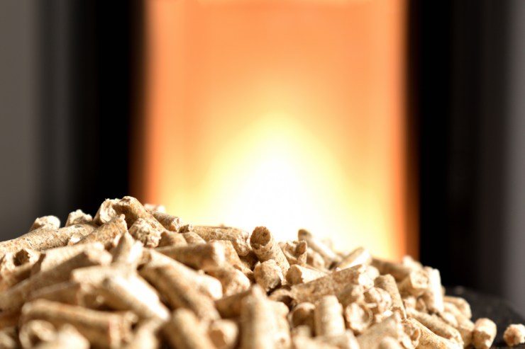 Il pellet in primo piano e come sfondo una stufa a pellet in funzione