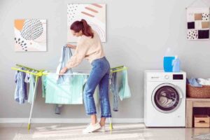 donna che stende i panni su stendino in casa