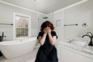 Un bagno come sfondo ed una persona a disagio in primo piano