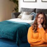 Un divano letto fatto ed una persona dubbiosa sulla sinistra
