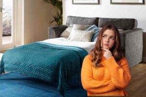 Un divano letto fatto ed una persona dubbiosa sulla sinistra