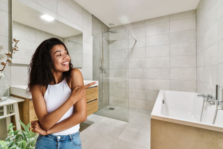 un bagno con una persona dentro che indica la doccia moderna a filo pavimento