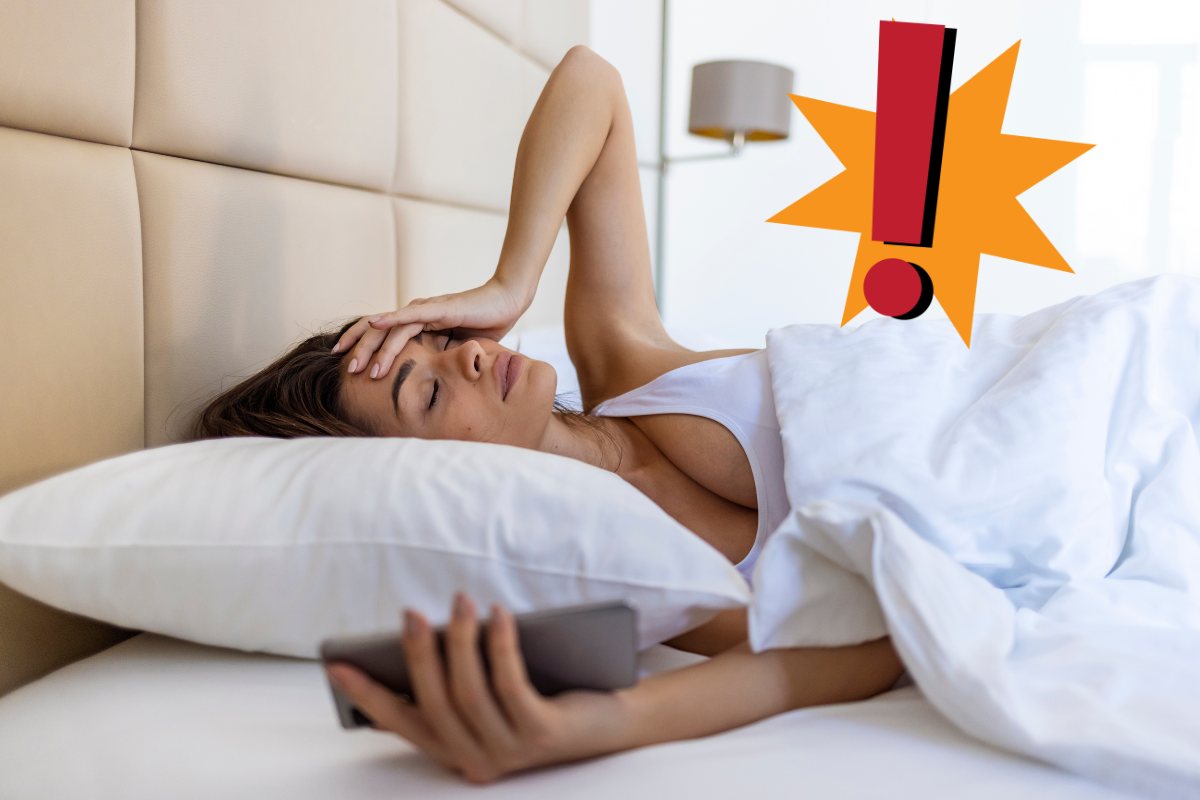Una ragazza sul letto che è stressata perché ha dormito male ed un punto esclamativo in alto a sinistra