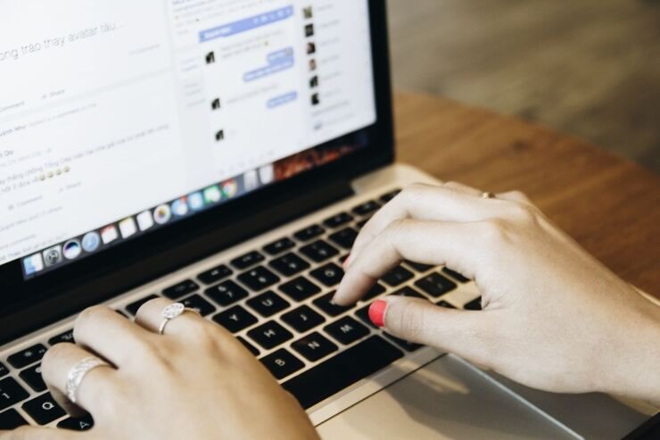 Donna digita su PC, Facebook sullo schermo