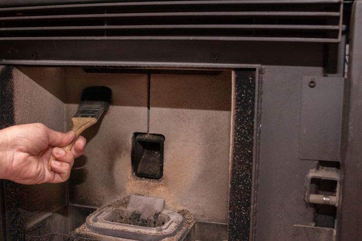 Una persona che pulisce la propria stufa a pellet
