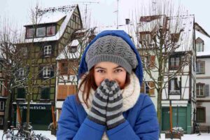 Una città innevata ed una persona infreddolita in primo piano