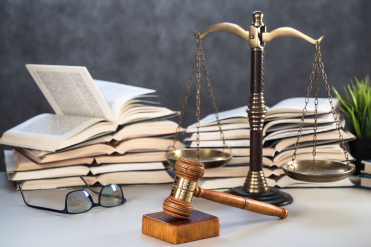 Dei libri di legge aperti, una bilancia di giustizia e un martello da giudice