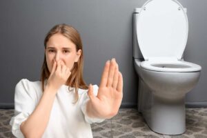 Una ragazza sulla sinistra che sente cattivo odore e sulla destra un WC