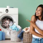 Una lavatrice con dei panni che cadono in una cesta ed una ragazza contenta che indica la lavatrice