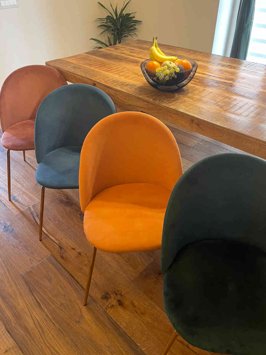 Sala da pranzo con tavolo in legno e sedie colorate in velluto