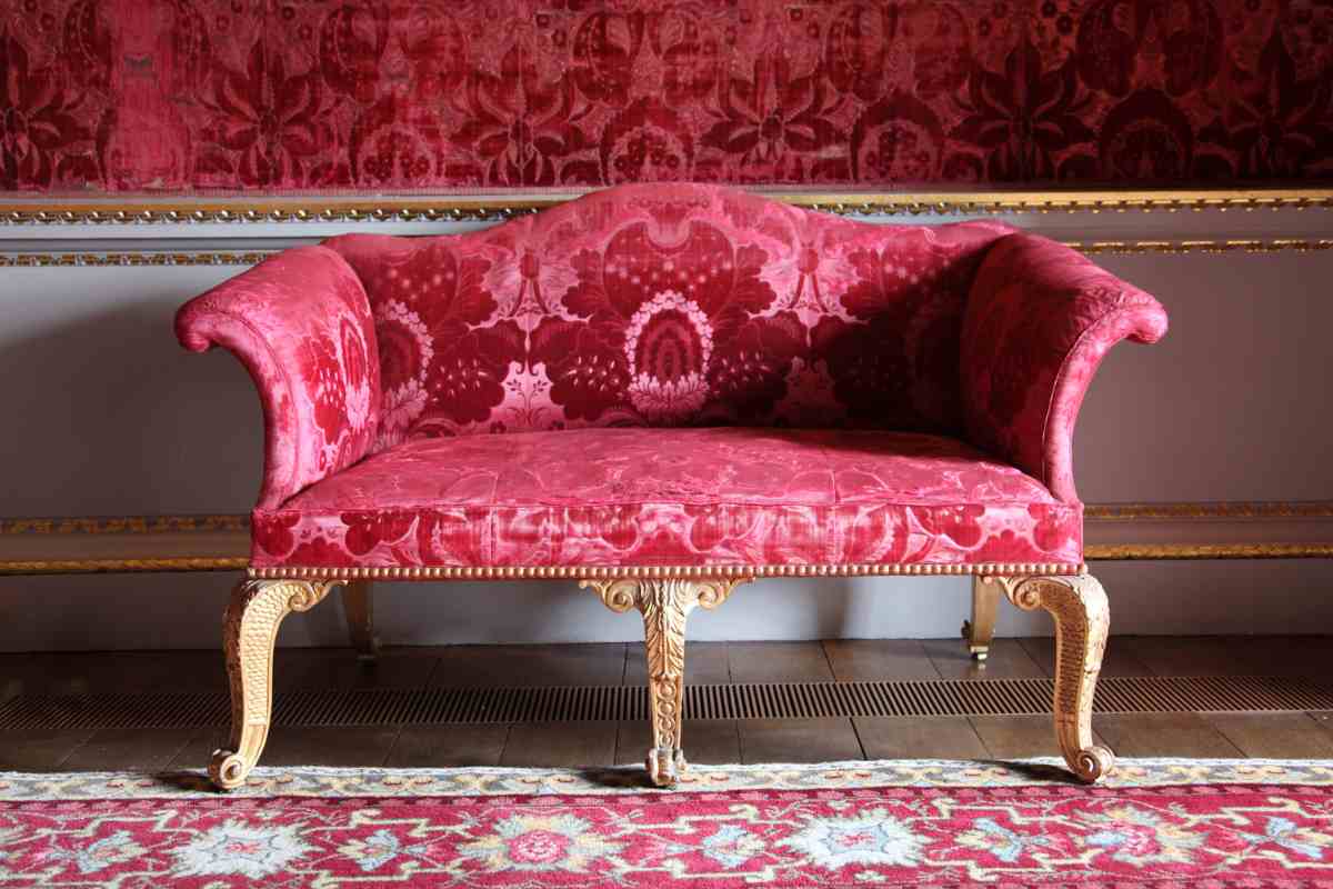 un sofa color amaranto con tessuto damascato e piedini dorati