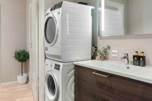 un angolo del bagno con asciugatrice sopra la lavatrice