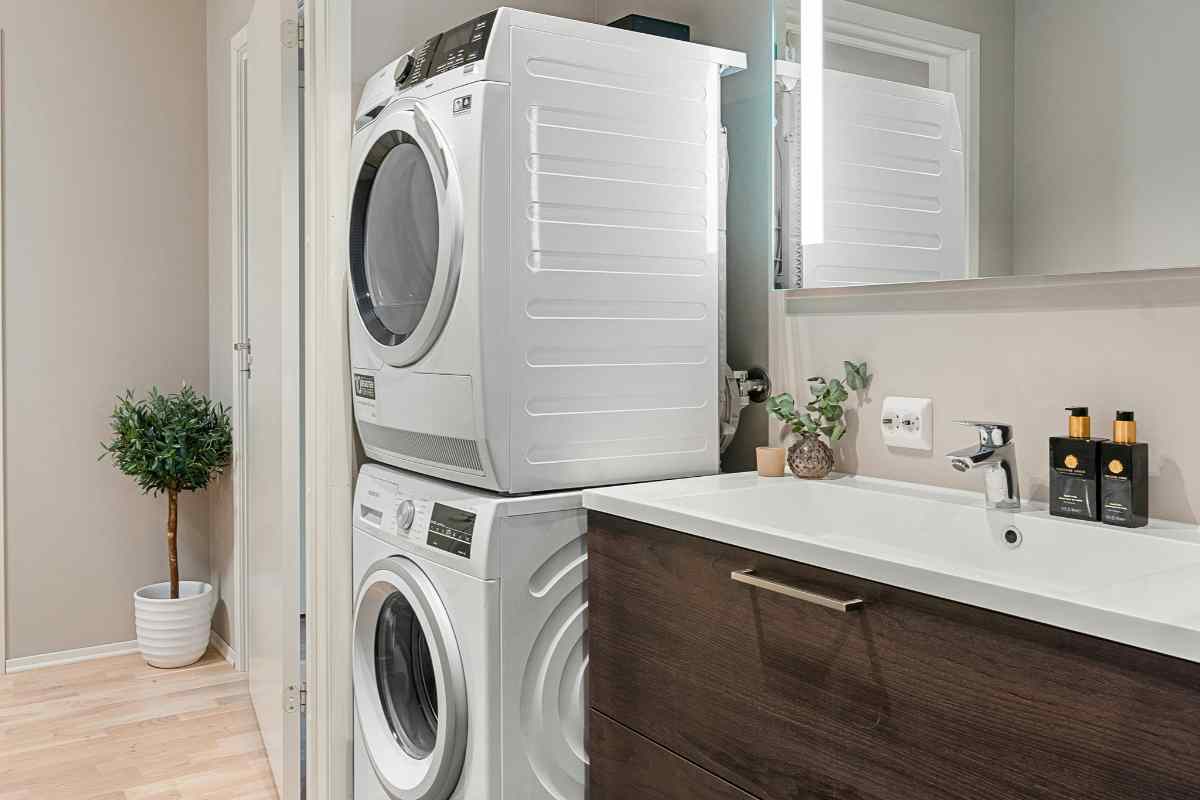 un angolo del bagno con asciugatrice sopra la lavatrice