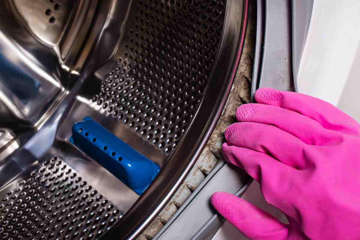 mano con guanto tende la gomma della guarnizione sporca della lavatrice