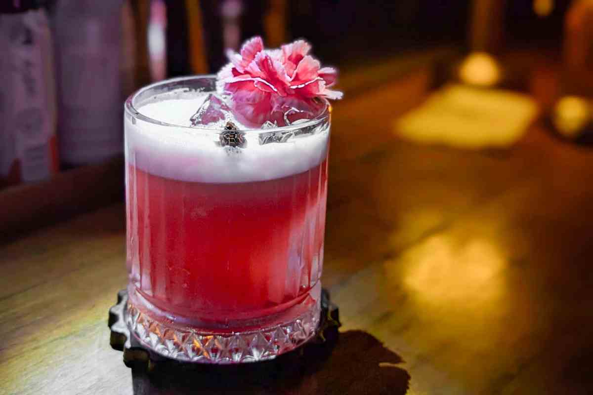 un cocktail in un bicchiere poggiato su un mobile bar industriale in legno