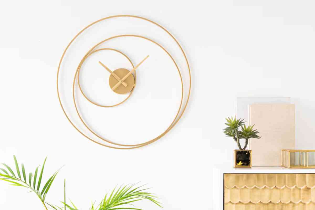 uno degli orologi di design in offerta Maisons du Monde sulla parete vicino a una madia dorata