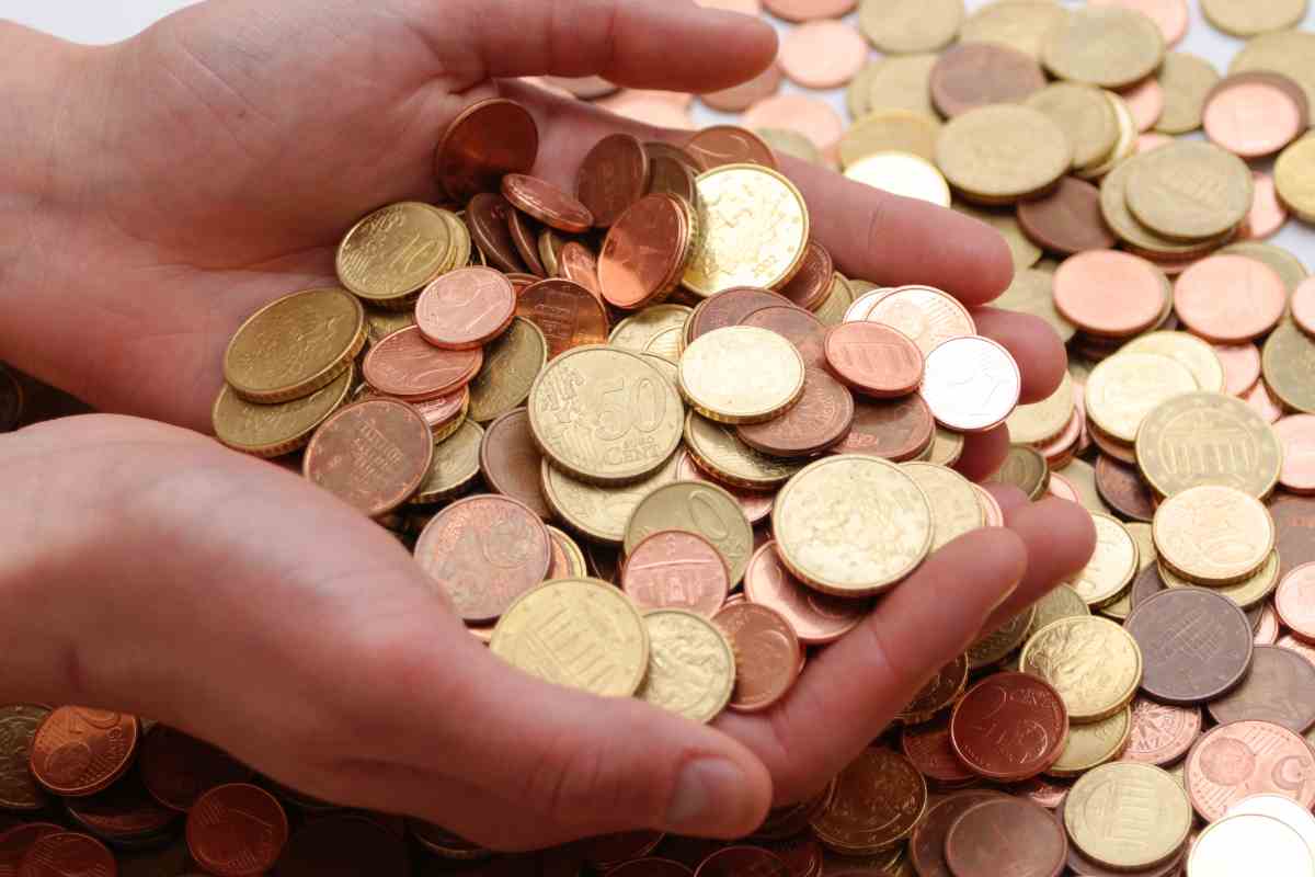 mani che raccolgono monete da un mucchio