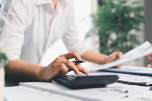 Una persona con documenti e fogli ed una calcolatrice che fa dei conti