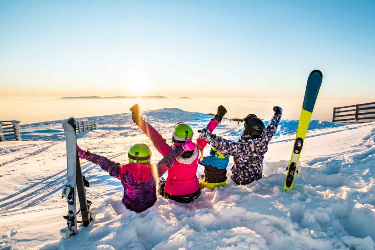 famiglia seduta sulla neve con gli sci conficcati