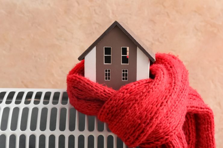 una casa in miniatura sopra il termosifone ed avvolta da una sciarpa