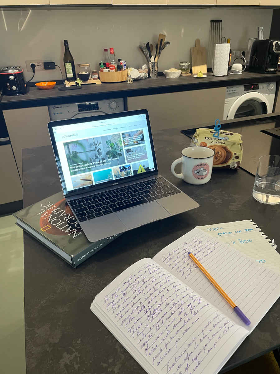 Isola della cucina usata per lo smart working con computer e quaderni