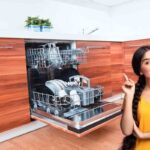 donna che indica in alto e lavatrice aperta in cucina