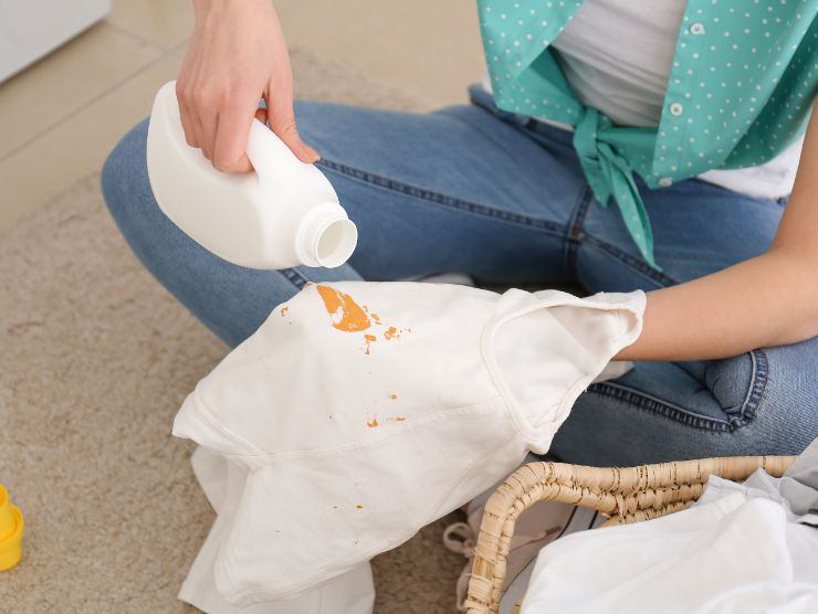 donna che versa candeggina su un tessuto macchiato