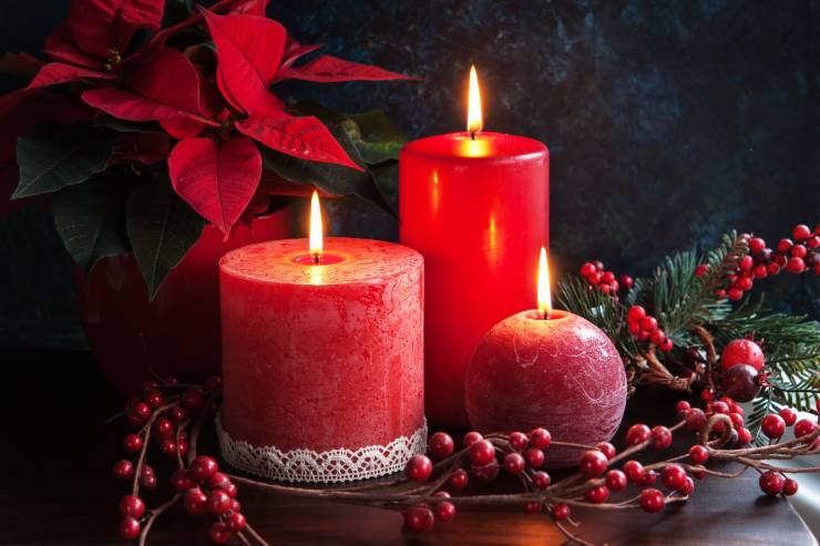 Delle candele natalizie accese circondate da altri arredi