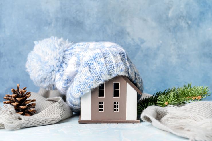 Una miniatura di una casa con un cappuccio di lana e circondata da una sciarpa