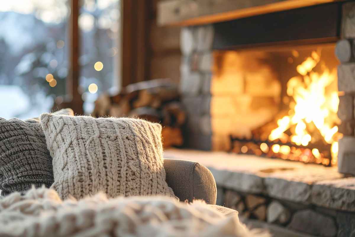 Divano con cuscini in primo piano e camino acceso sullo sfondo