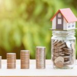 Casa su barattolo di vetro con monete, fila di monete impilate