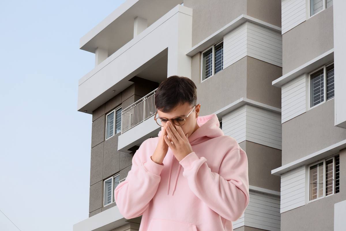 Un condominio sullo sfondo ed in primo piano un condomino preoccupato