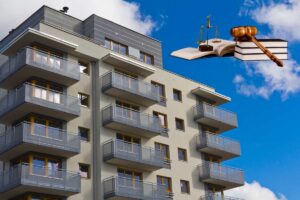 Un condominio ed in alto a sinistra dei libri di legge con una bilancia ed un martello da giudice