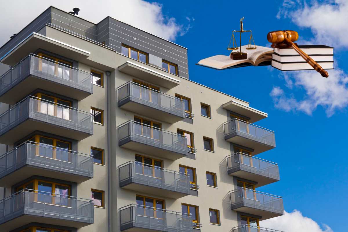 Un condominio ed in alto a sinistra dei libri di legge con una bilancia ed un martello da giudice