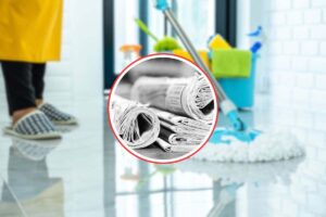 persona che pulisce il pavimento e in primo piano dei fogli di giornale in un cerchio