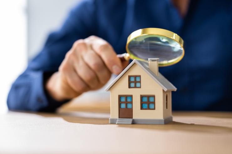 Un uomo che osserva con una lente una miniatura di una casa