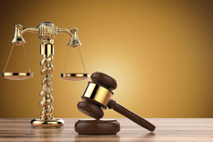Un tavolo con sopra una bilancia di giustizia ed un martello da giudice