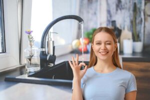 donna che fa ok e rubinetto nero aperto in cucina