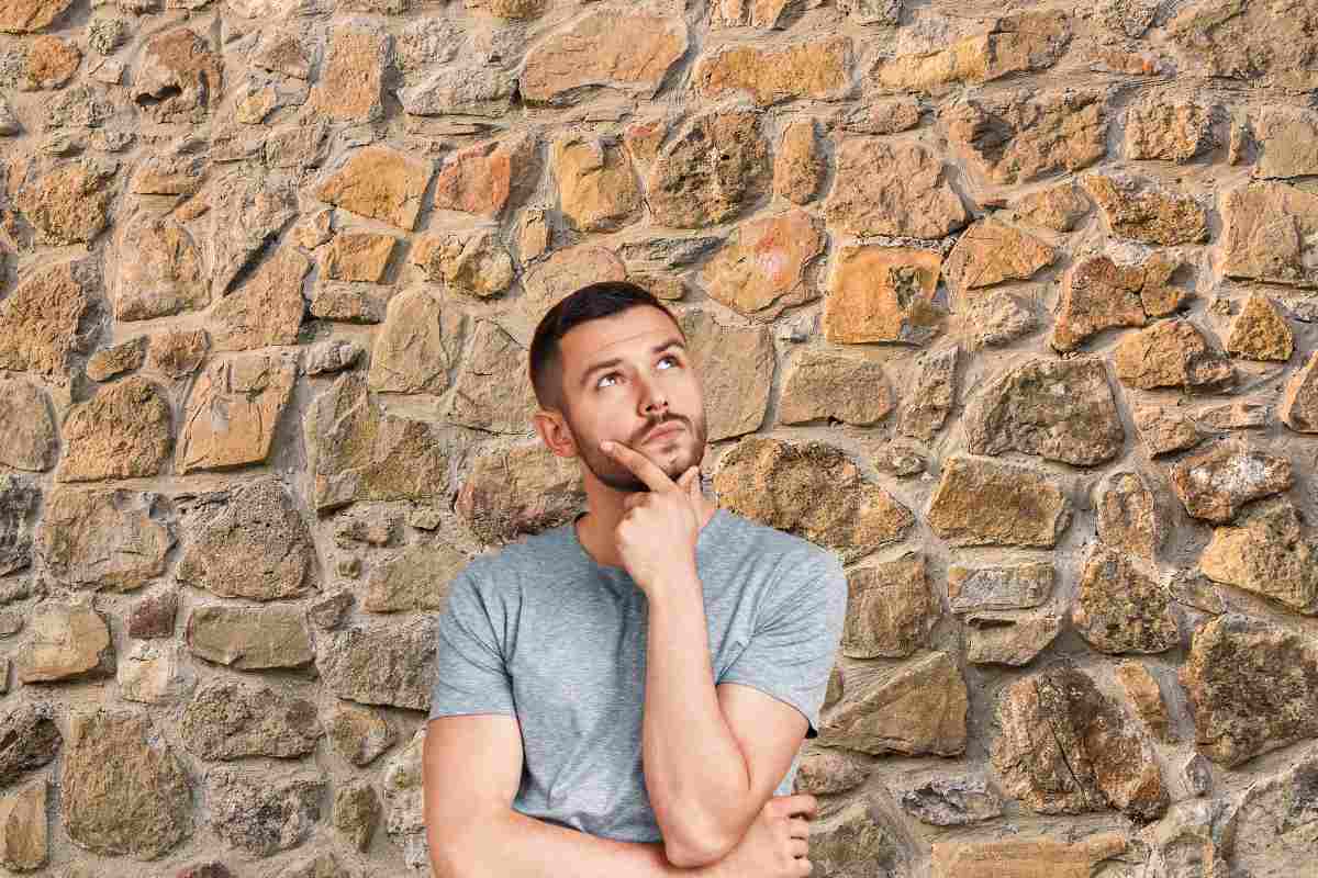 Uno sfondo di un muro a sacco e un ragazzo pensieroso in primo piano