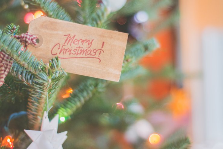 Un albero di natale con sopra un foglietto con scritto "Merry Christmas"