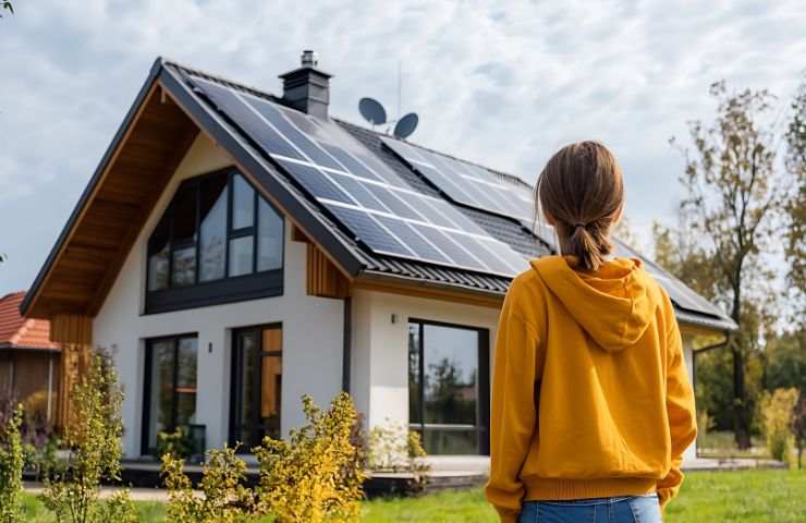 donna di spalle e casa co pannelli solari sul tetto