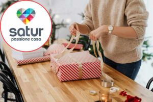 donna che impacchetta regalo di natale e logo satur