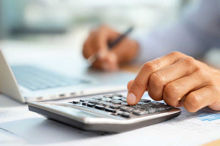 Un uomo che sta facendo i conti con computer e calcolatrice