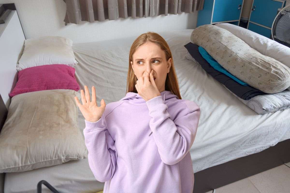 donna che si tappa il naso per il cattivo odore che proviene da cuscini sporchi e ingialliti